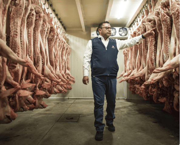 Vendedor recorre pasillos con canales de cerdo 